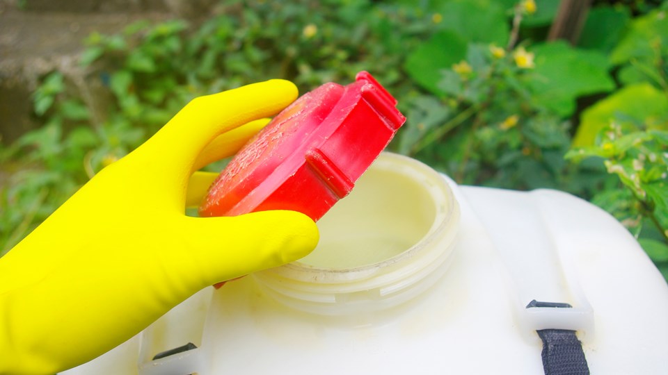 Gloved hand removing lid from a hazardous substance/chemical container