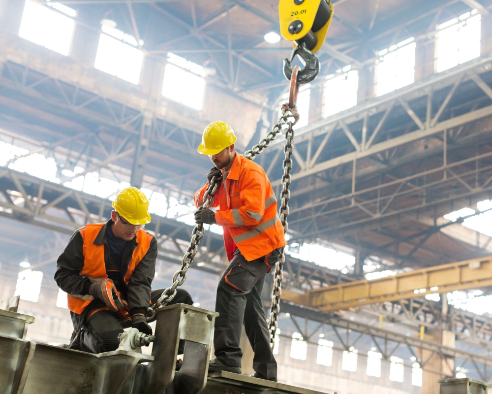 Workers using a chain sling under an overhead gantry crane during crane training session