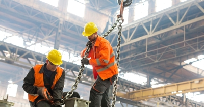 Workers using a chain sling under an overhead gantry crane during crane training session