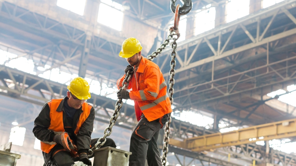 Workers using a chain sling under an overhead gantry crane during crane training session